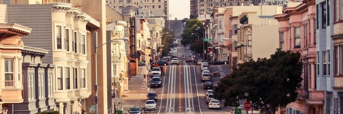 Streetcar on a steep hill in San Francisco with classic buildings and cars lined up.