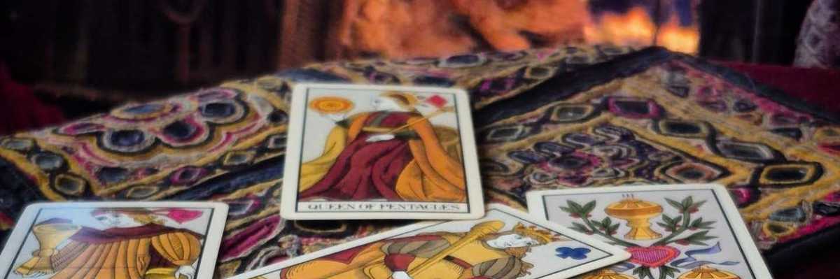 tarot cards on a table with a colorful tablecloth in front of a fireplace