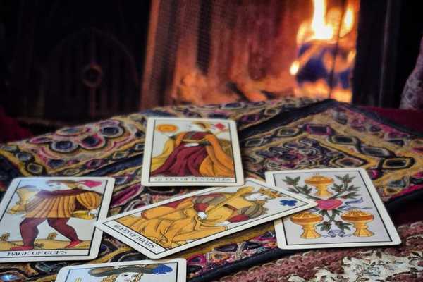 tarot cards on a table with a colorful tablecloth in front of a fireplace