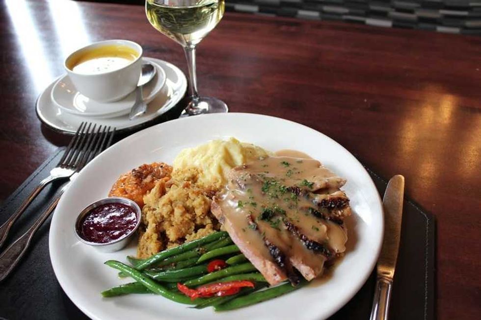 Thanksgiving meal with turkey, gravy, stuffing, beans, cranberry sauce, soup, and wine.