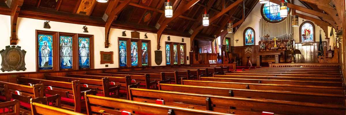 the inside of a chapel with redwood benches & beams and Tiffany stained glass