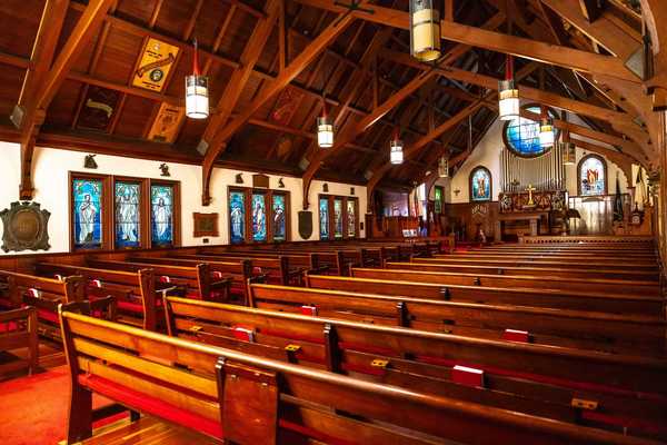 the inside of a chapel with redwood benches & beams and Tiffany stained glass