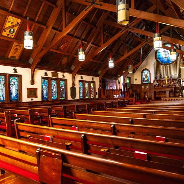 the inside of a chapel with redwood benches & beams and Tiffany stained glass