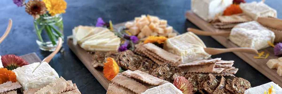 three cheese boards covered with different cheeses and crackers