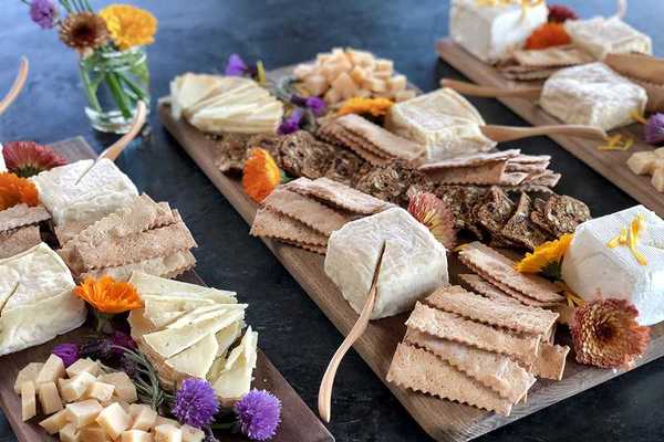 three cheese boards covered with different cheeses and crackers