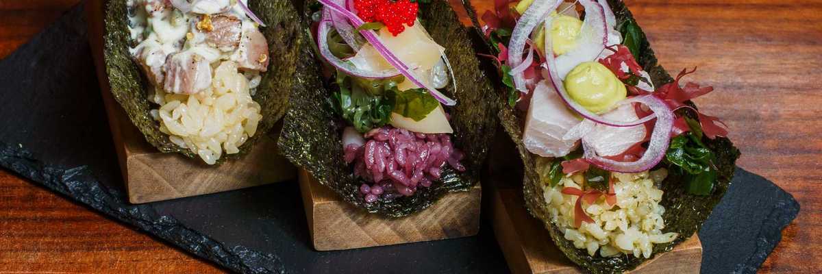 three Japanese Peruvian-style handrolls on a slate tray