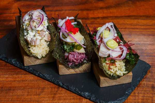 three Japanese Peruvian-style handrolls on a slate tray