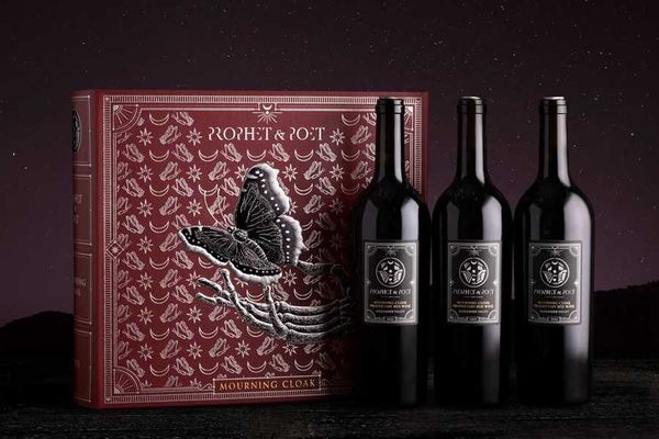 Three wine bottles beside a detailed red box with a butterfly design.