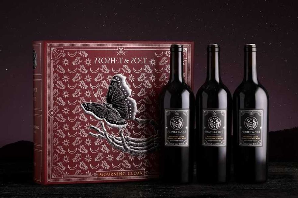 Three wine bottles beside a detailed red box with a butterfly design.