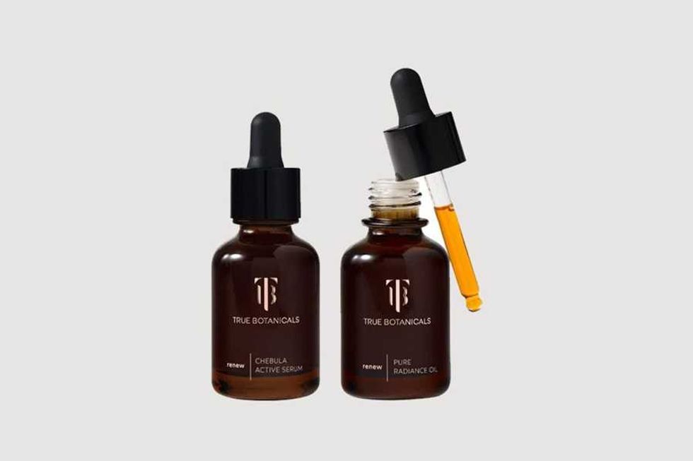 Two brown serum bottles with droppers labeled True Botanicals on a gray background.