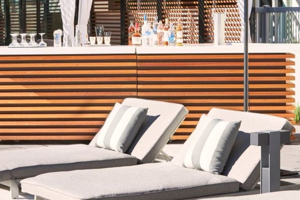 Two lounge chairs with striped cushions by a wooden outdoor bar.