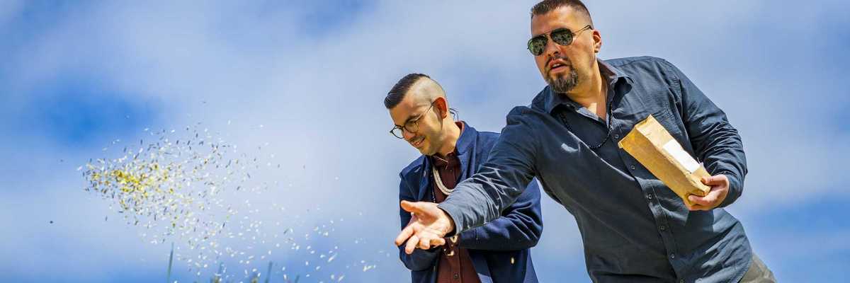 two men with glasses throwing seeds over a mound of shells and plants