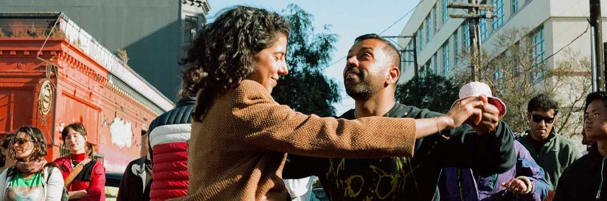 two people dancing in the street with passersby