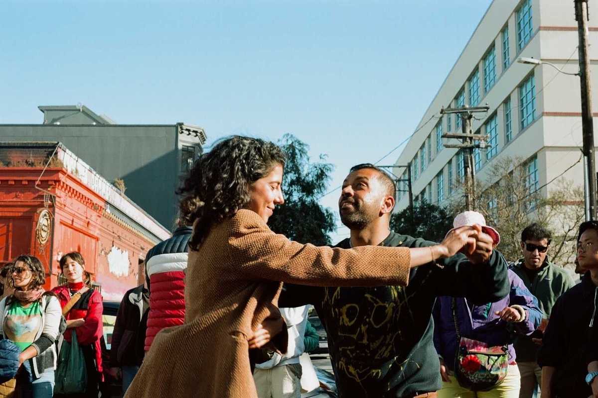 two people dancing in the street with passersby