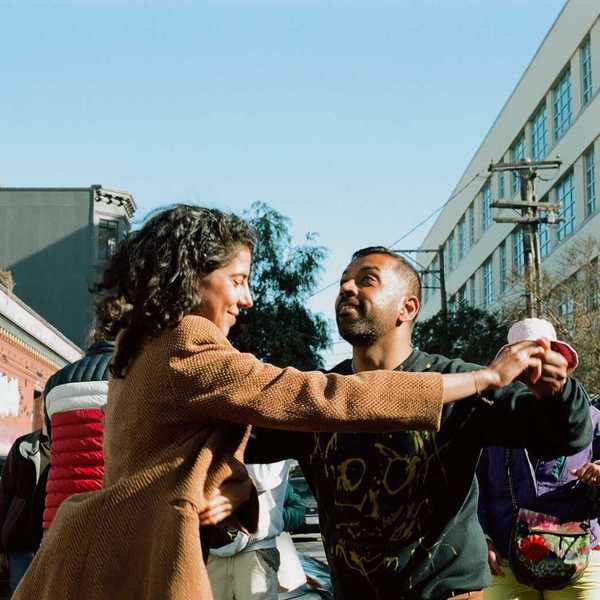two people dancing in the street with passersby