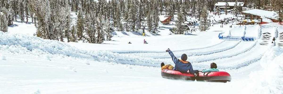 Two people in tubes gliding down the snow in the mountains