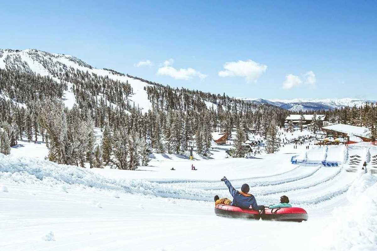 Two people in tubes gliding down the snow in the mountains