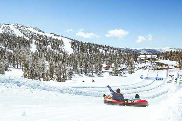 Two people in tubes gliding down the snow in the mountains