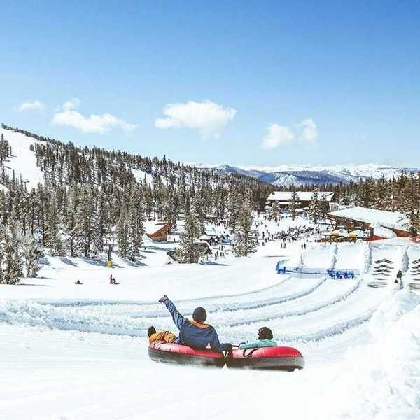 Two people in tubes gliding down the snow in the mountains