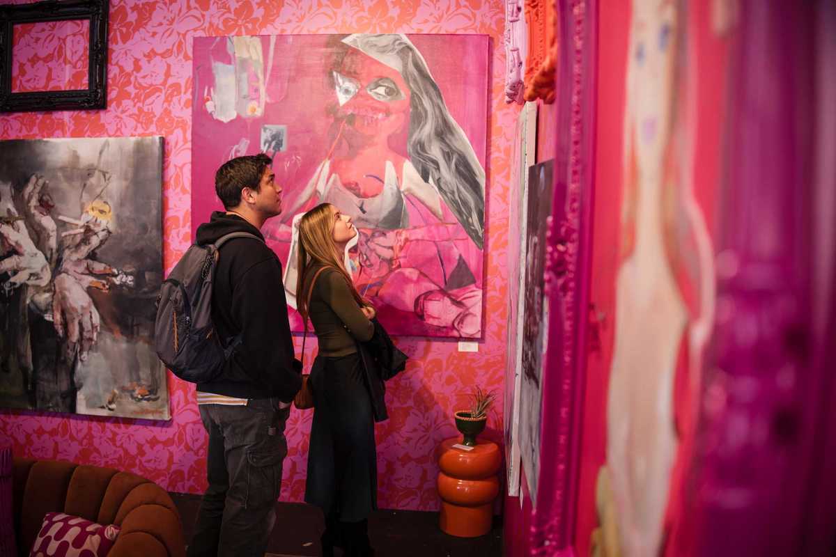 two people looking at art in a pink gallery