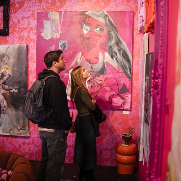 two people looking at art in a pink gallery