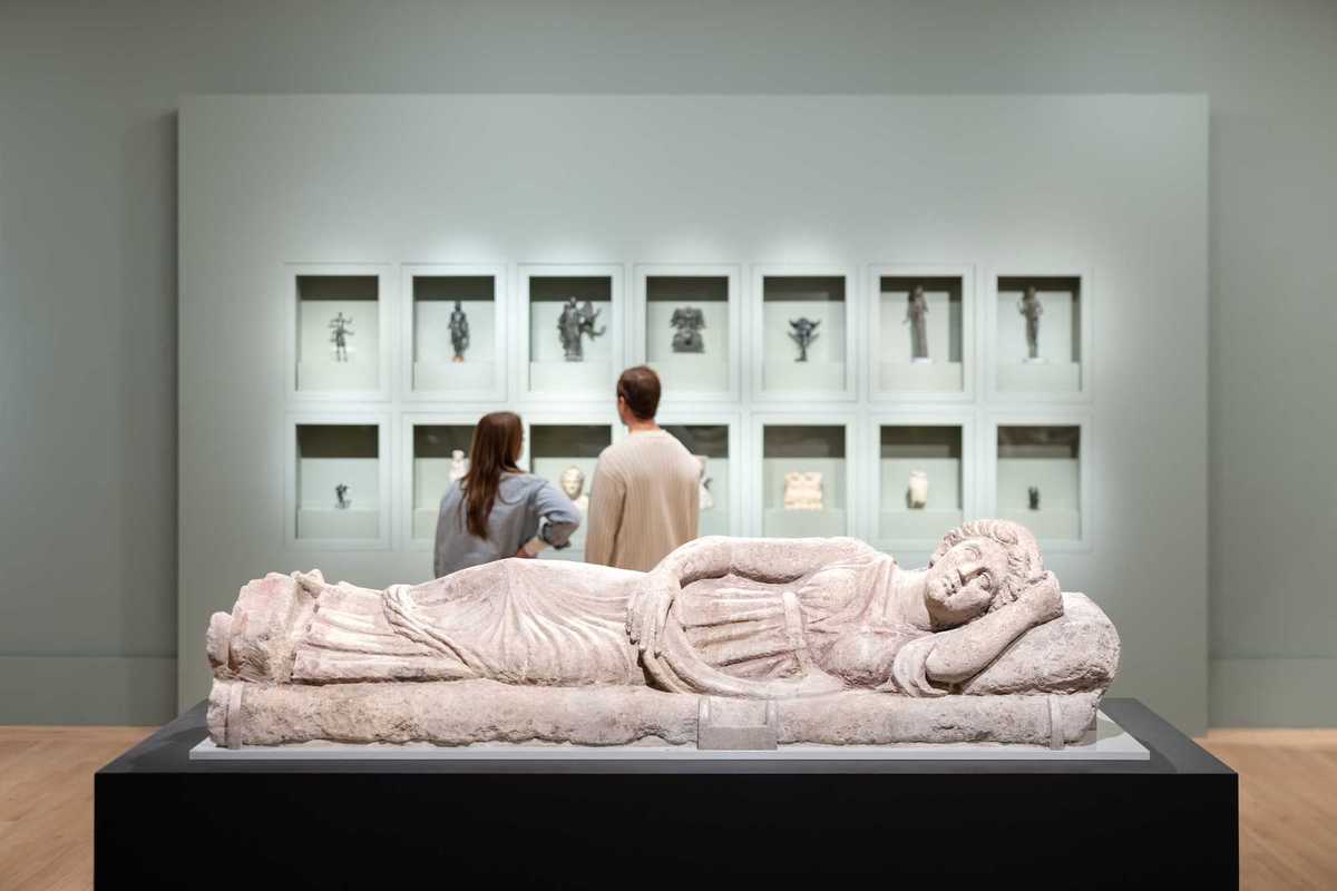 two people looking at artifacts in a museum with a prostrate sculpture in the foreground