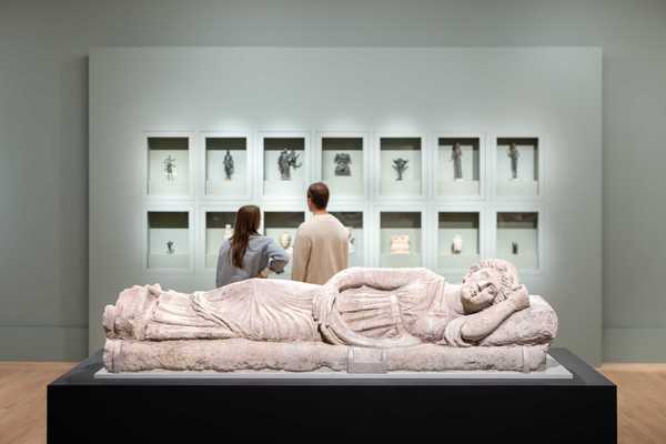 two people looking at artifacts in a museum with a prostrate sculpture in the foreground