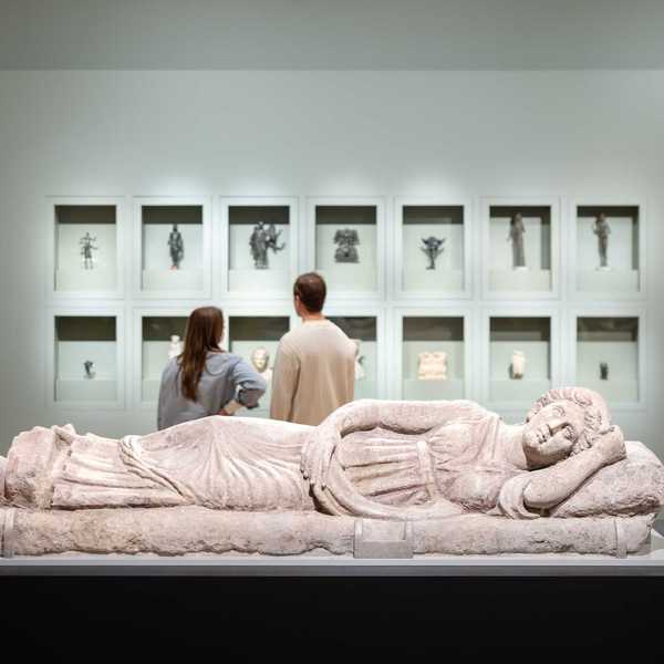 two people looking at artifacts in a museum with a prostrate sculpture in the foreground