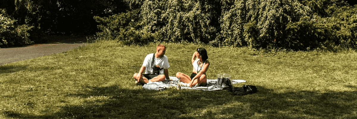 two people sitting on a picnic blanket in the park