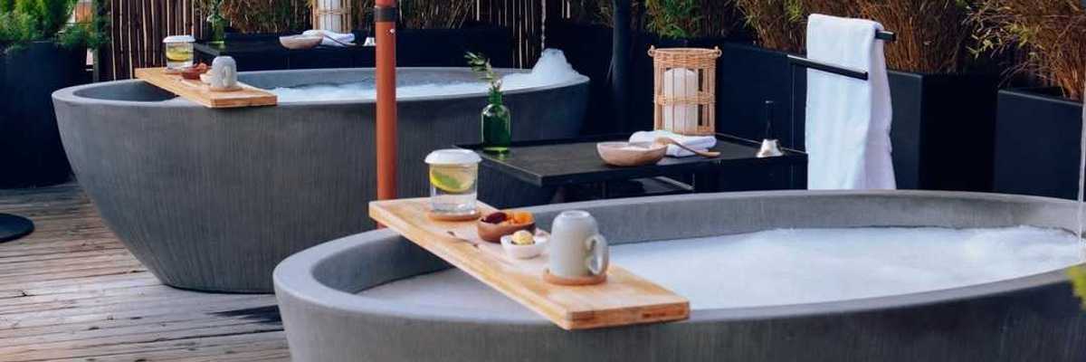two stone tubs on a rooftop with greenery and towels