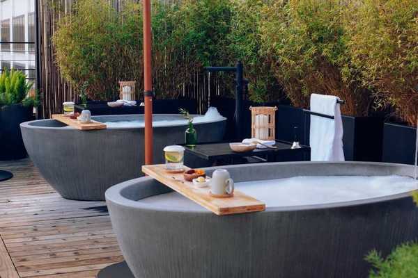 two stone tubs on a rooftop with greenery and towels