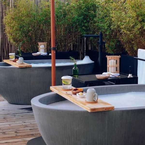 two stone tubs on a rooftop with greenery and towels