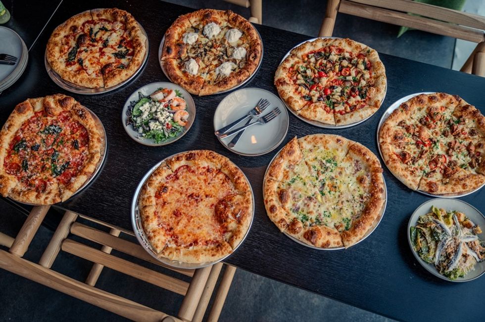 Variety of pizzas and salads on a black table.