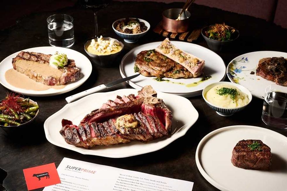 Variety of steaks and sides on plates, including greens, mashed potatoes, and macaroni.