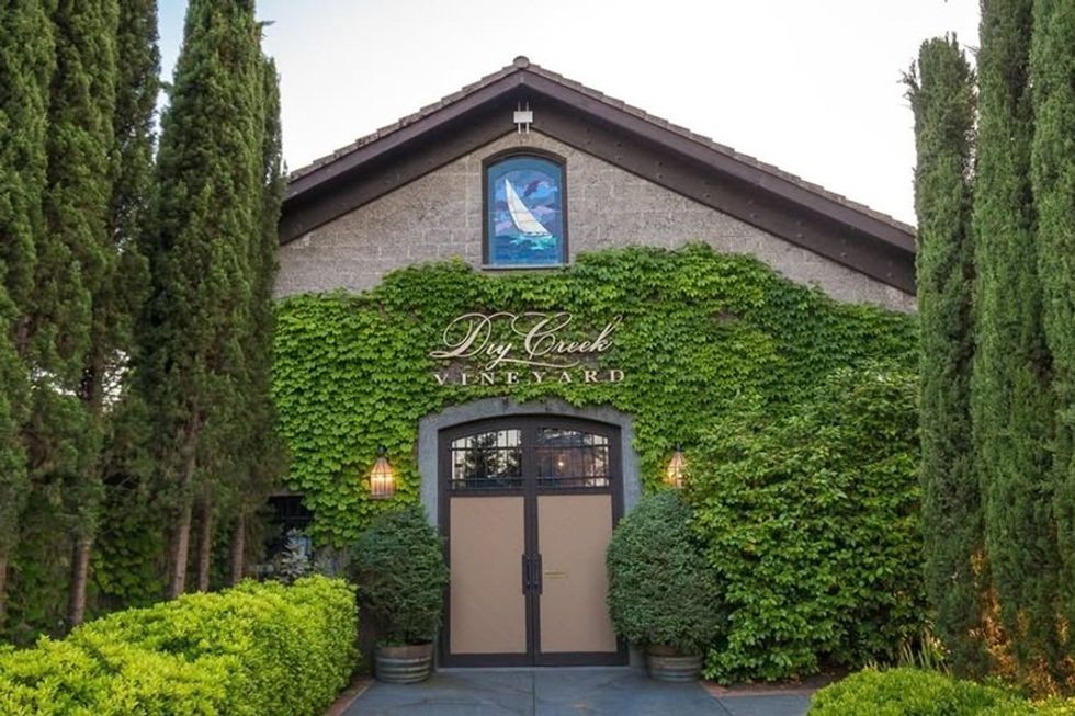 Vine-covered entrance of Dry Creek Vineyard with cypress trees and a sailboat mural above.