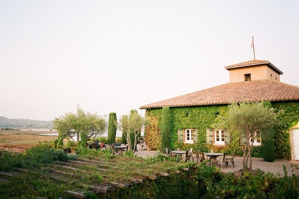 Vine-covered house with garden patio and distant mountains.