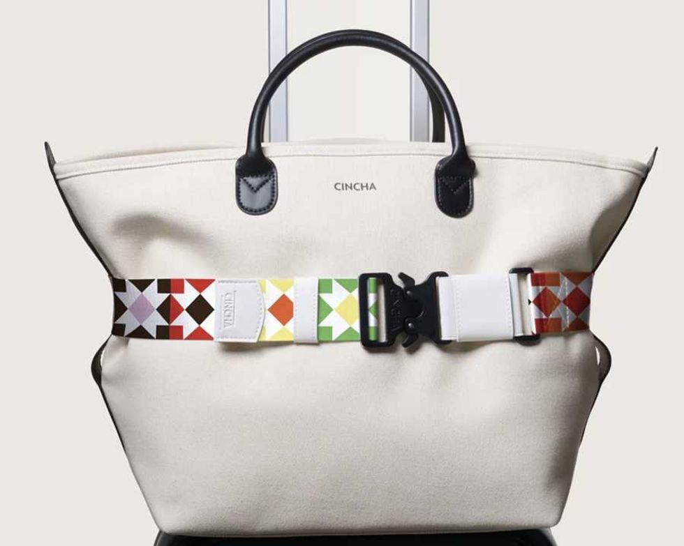 White tote bag with geometric patterned strap around it.