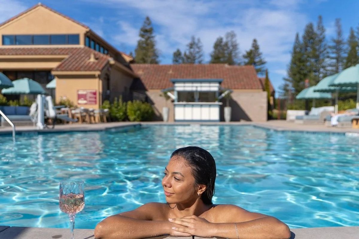 Woman in a pool with a glass of wine next to her