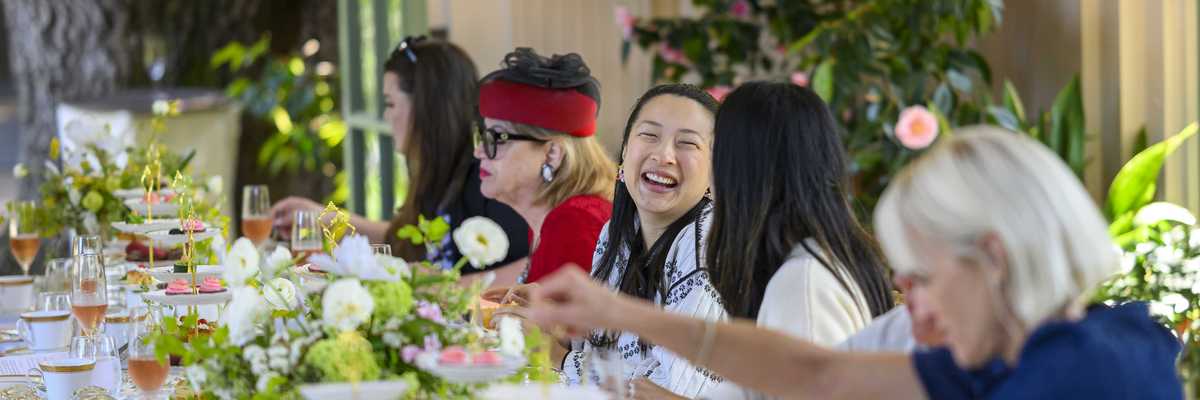 women sitting at a long table with flowers and tea
