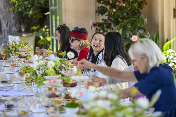 women sitting at a long table with flowers and tea