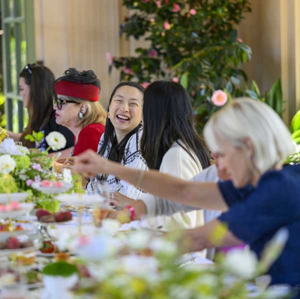 women sitting at a long table with flowers and tea