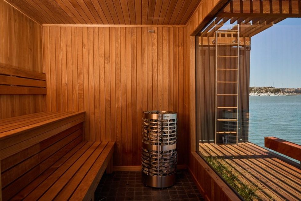 Wooden sauna interior with view of water through a large window.